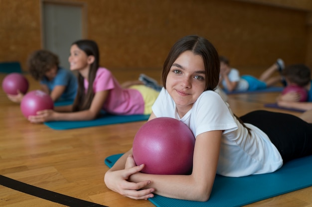 Crianças com tacadas médias em tapetes de ioga com bolas