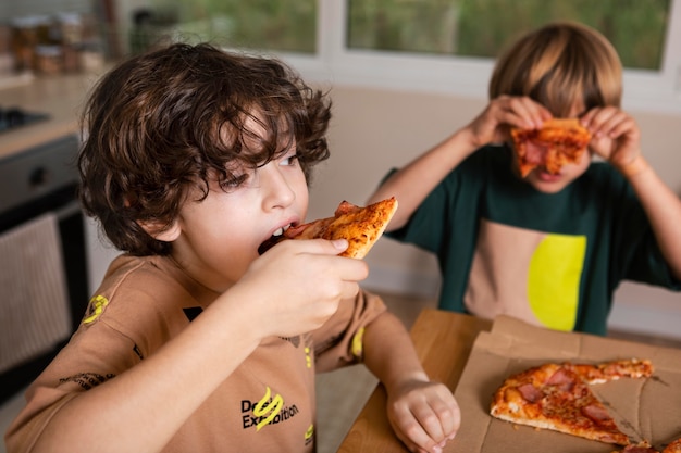Crianças comendo pizzas juntas
