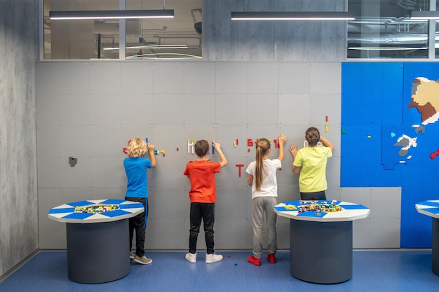 Crianças de costas para a câmera fazendo mosaicos na parede