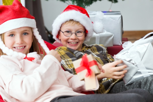 Crianças de sorriso com presentes e chapéu de Santa