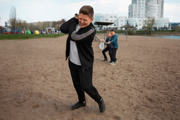 Foto grátis crianças de tiro completo jogando cabo-de-guerra na praia
