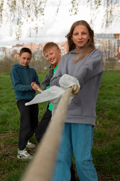 Crianças de tiro completo jogando cabo de guerra no parque