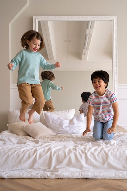 Crianças de tiro completo pulando na cama