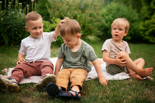 Crianças de tiro completo sentadas do lado de fora