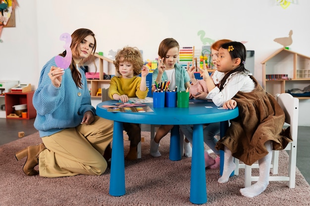 Foto grátis crianças de tiro completo sentados juntos à mesa