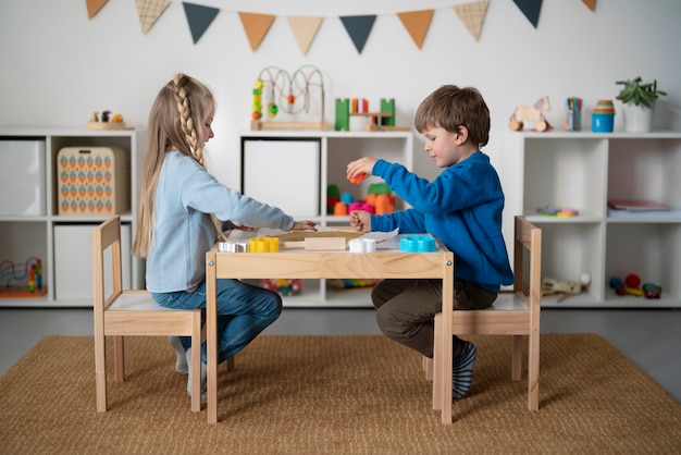 Foto grátis crianças de tiro completo sentados juntos à mesa