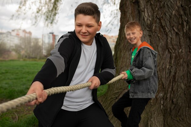 Crianças de tiro médio brincando de cabo de guerra no parque