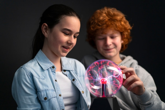 Foto grátis crianças de tiro médio interagindo com uma bola de plasma