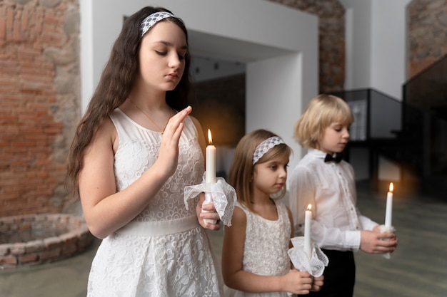 Crianças de tiro médio rezando com velas