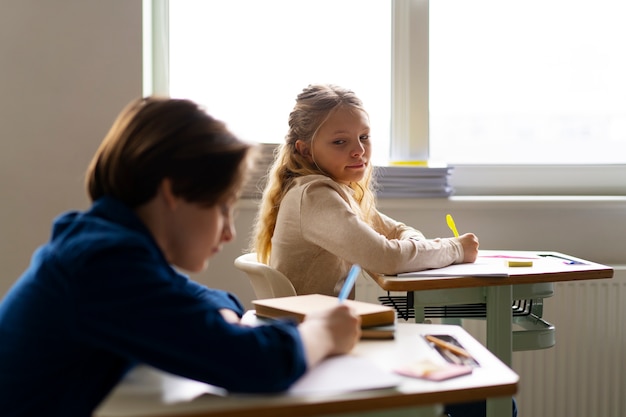 Crianças de tiro médio trapaceando na escola