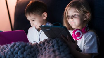 Crianças em casa com tablet e laptop