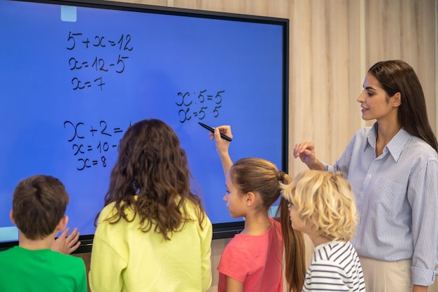 Crianças escrevendo no quadro-negro e atento professor assistindo