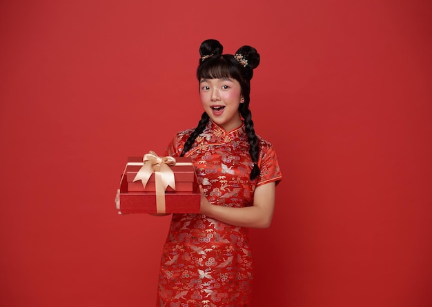 Foto grátis crianças felizes menina asiática em traje tradicional vermelho dando caixa de presente para abençoar o ano novo chinês 2024
