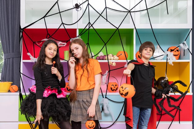 Crianças felizes, meninos e meninas em frente à decoração da festa de Halloween e segurando abóbora Jacko'lantern