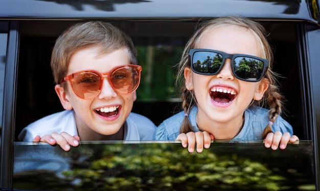 Crianças felizes, olhando pela janela do carro