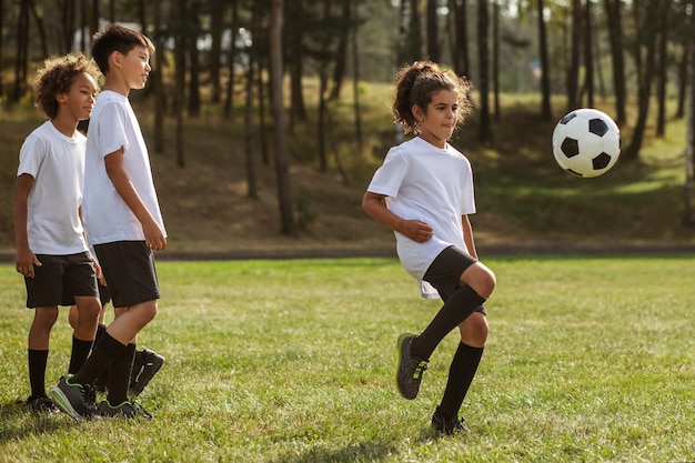 Foto grátis crianças jogando futebol supervisionadas por treinador de futebol