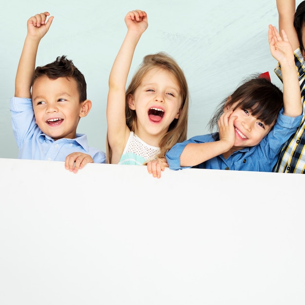 Crianças levantando os braços e torcendo com maquete de tabuleiro