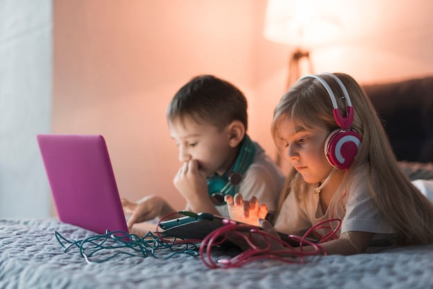 Crianças na cama com laptop e tablet