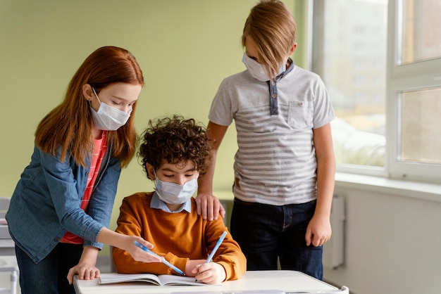 Crianças na escola aprendendo com máscaras médicas