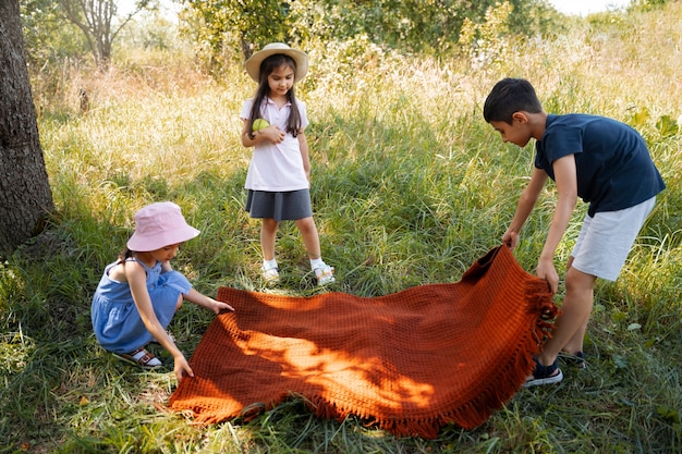 Crianças passando tempo juntos ao ar livre no cobertor curtindo a infância