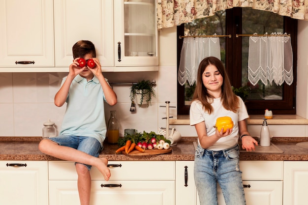 Crianças posando com legumes na cozinha