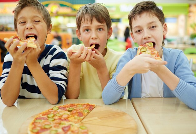 Crianças que apreciam a pizza