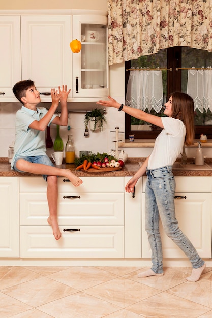 Crianças se divertindo com legumes na cozinha