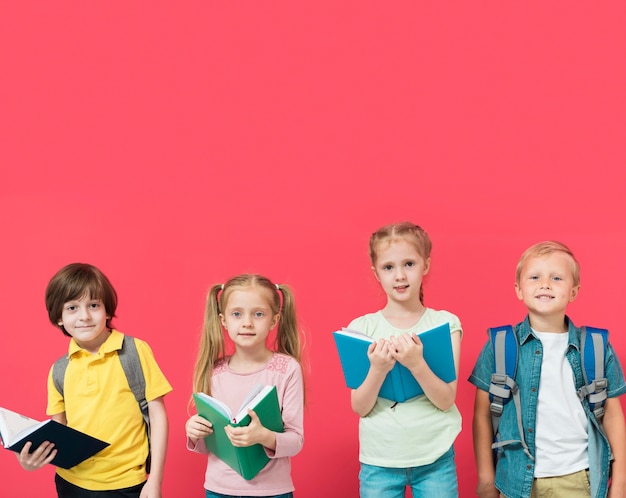 Crianças segurando seus livros com fundo vermelho