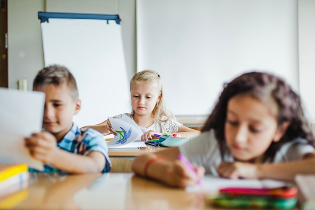 Crianças sentadas em sala de aula estudando
