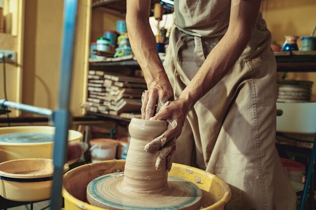 Criando um pote ou vaso de argila branca close-up. Mestre pote. Mãos de homem fazendo macro de jarro de barro.