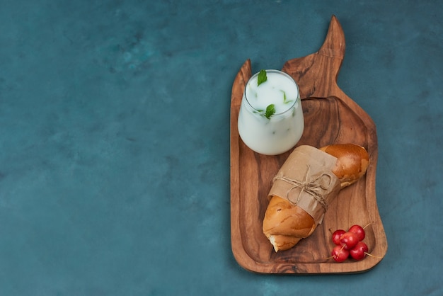 Croissant com uma xícara de leite e cerejas.