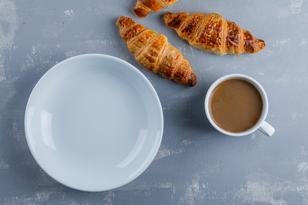 Croissant com xícara de café, prato vazio, plana leigos.
