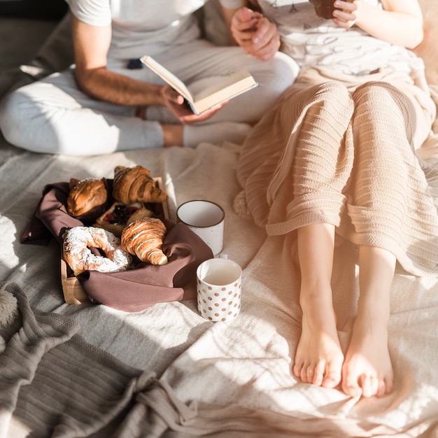 Croissant e café com casal sentado na cama