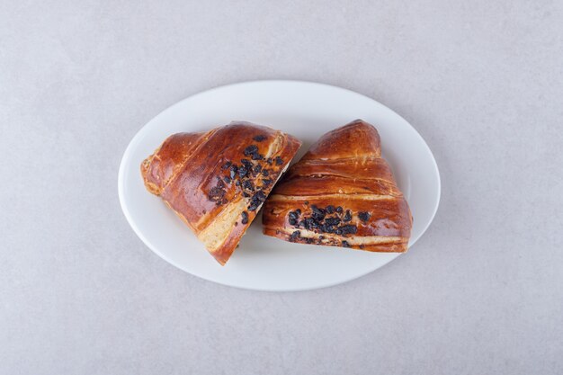 Croissant fatiado caseiro com chocolate num prato, no mármore.