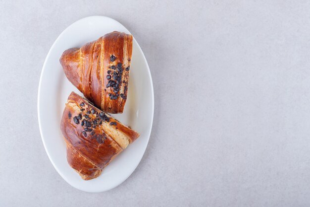 Croissant fatiado caseiro com chocolate num prato, no mármore.