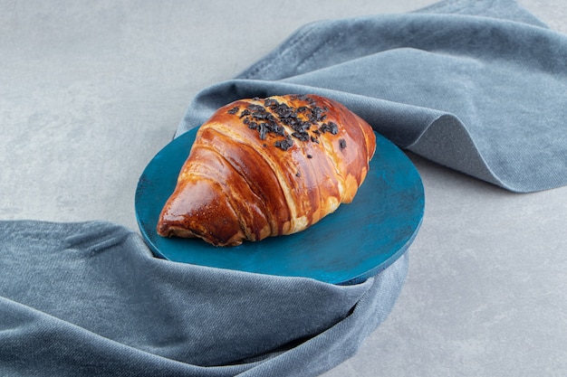 Croissant fresco decorado com gota de chocolate no quadro azul.