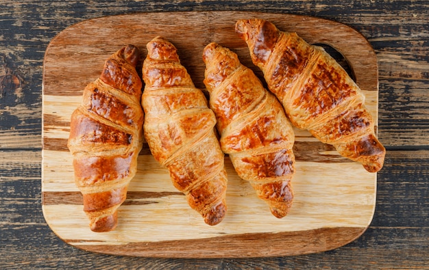 Croissant na tábua de madeira e corte. configuração plana.