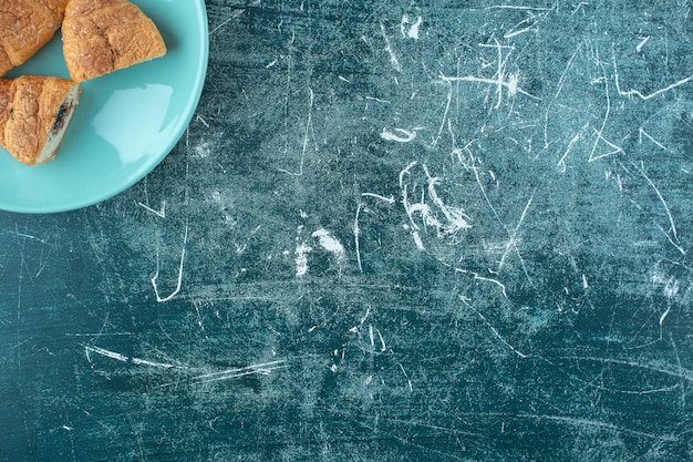 Foto grátis croissants caseiros num prato, na mesa azul.