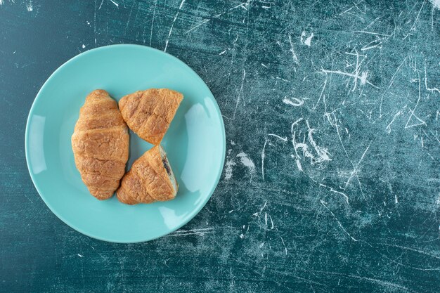 Croissants caseiros num prato, sobre o fundo azul. Foto de alta qualidade