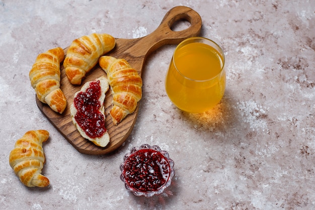 Croissants caseiros saborosos frescos com geléia de framboesa em cinza-branco. Pastelaria francesa