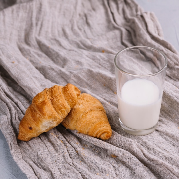 Foto grátis croissants e copo de leite na têxtil de saco amassado