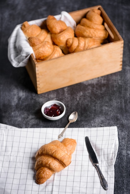 croissants em caixa de madeira e geléia de lado na mesa cinza