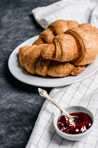 croissants no prato redondo branco e panela com geléia de lado