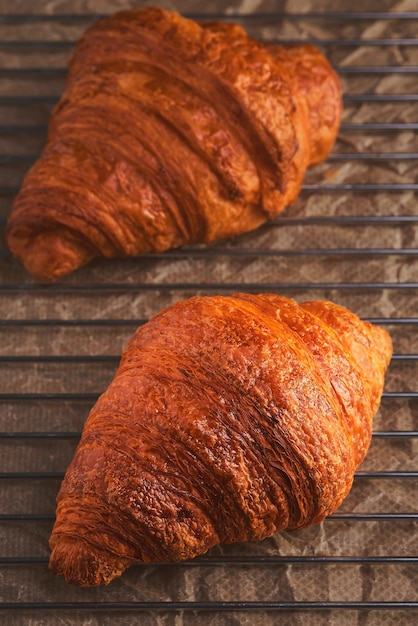 Croissants recém-assados em um rack de resfriamento Close up vertical e foco seletivo em um croissant Pastel fresco para café da manhã francês