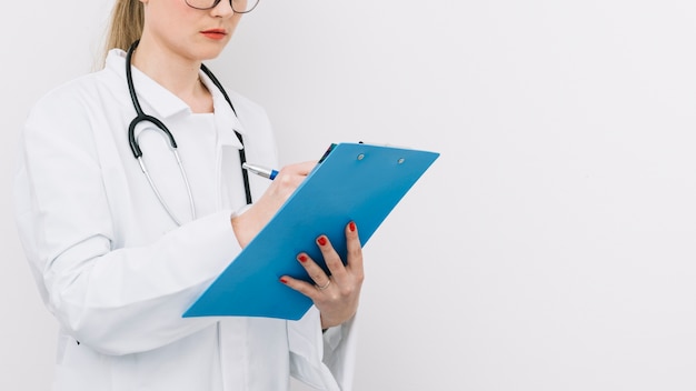 Foto grátis crop doctor writing on clipboard