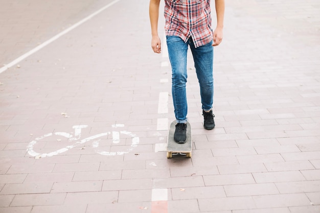 Crop teenager skateboarding perto da pista de bicicleta