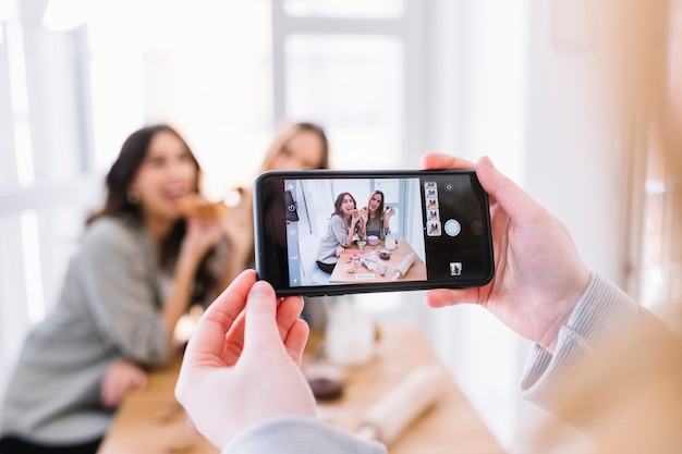 Crop woman taking picture of friends