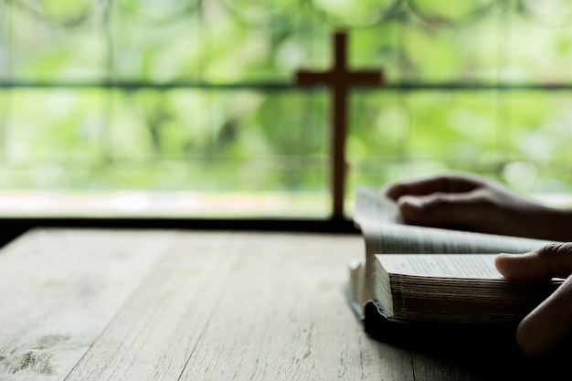 Cruzes que se abrem acima da bíblia em uma mesa de madeira