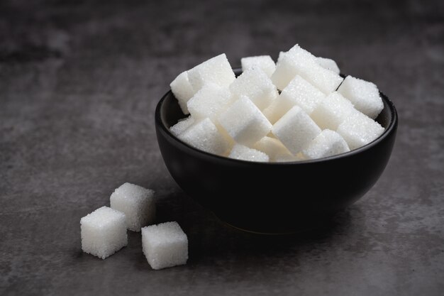 Cubos de açúcar branco em uma tigela na mesa.