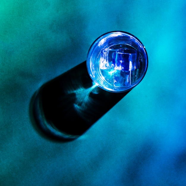 Cubos de gelo no vidro azul com sombra no fundo colorido